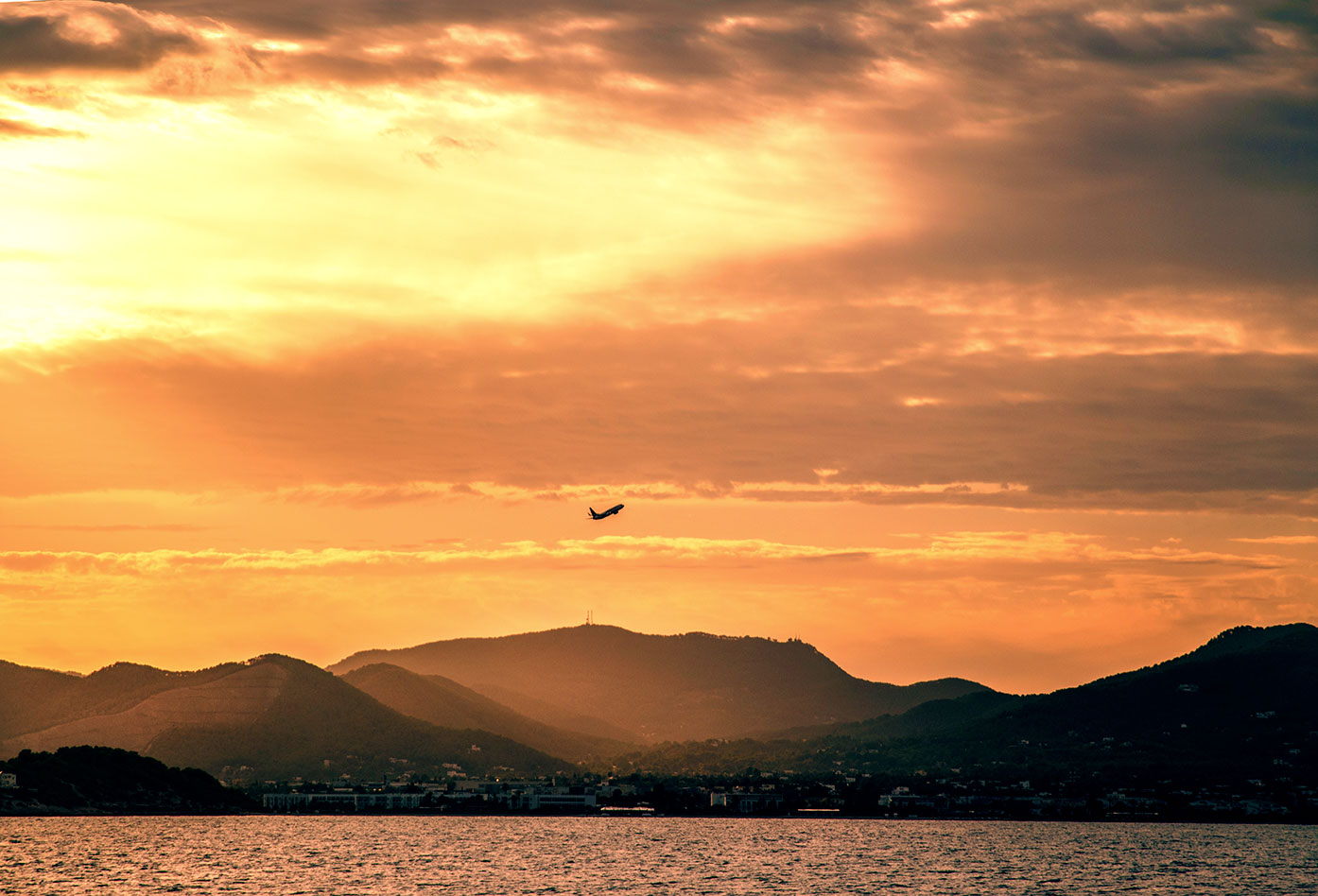 Ibiza city view from the sea by sunset with plane taking off, Balearic Islands, Catalonia, Spain. (Nos Dren).