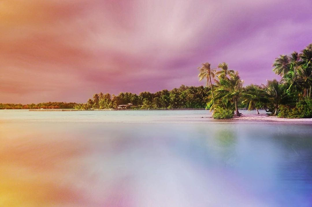 French Polynesia, Bora Bora island, amazing colorful sky and reflection on the blue lagoon took from the atoll with many palm trees and coco trees. (Nos Dren)